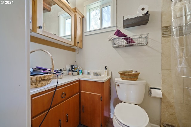 bathroom featuring toilet, vanity with extensive cabinet space, and a tile shower