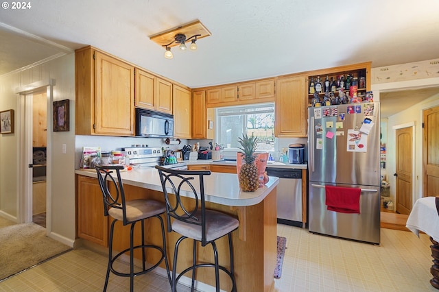 kitchen featuring crown molding, a breakfast bar, light tile floors, and stainless steel appliances