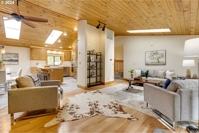 living room with a skylight, ceiling fan, wood ceiling, and light hardwood / wood-style floors