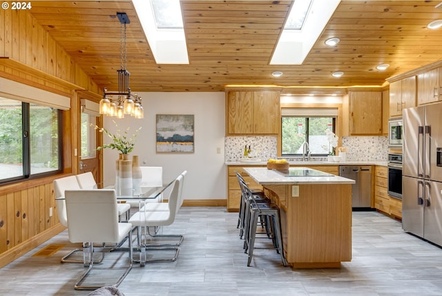 kitchen with a skylight, a center island, decorative light fixtures, stainless steel appliances, and sink