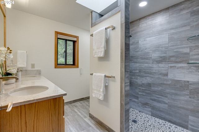 bathroom with tiled shower, hardwood / wood-style floors, and vanity