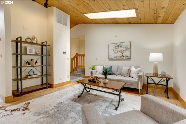 living room with wood ceiling, high vaulted ceiling, light wood-type flooring, and a skylight