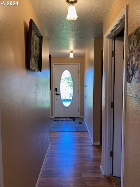 doorway to outside with a textured ceiling and hardwood / wood-style floors