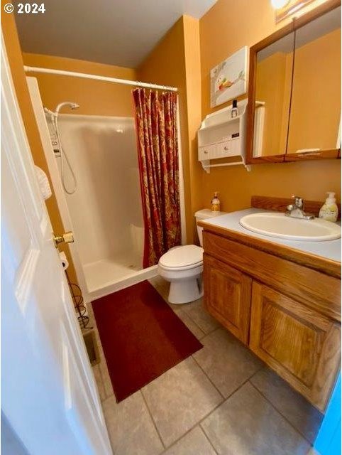 bathroom with vanity, tile patterned flooring, toilet, and walk in shower