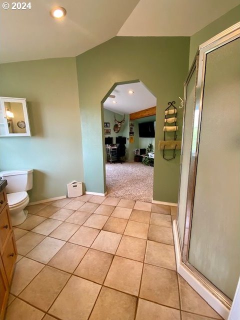 bathroom with tile patterned floors, lofted ceiling, vanity, and toilet