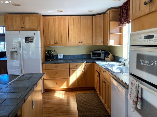 kitchen featuring white appliances, light hardwood / wood-style floors, tile counters, and sink