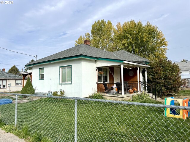 bungalow-style home with a front yard and covered porch