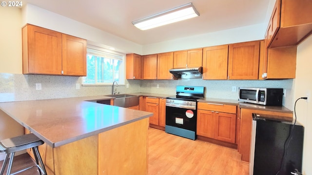 kitchen featuring light hardwood / wood-style flooring, decorative backsplash, appliances with stainless steel finishes, a kitchen bar, and kitchen peninsula