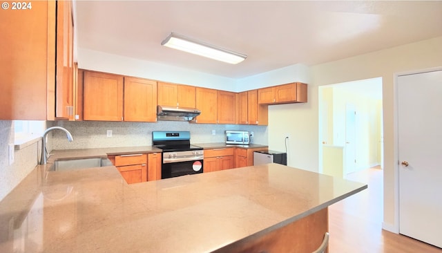 kitchen featuring backsplash, sink, light hardwood / wood-style floors, kitchen peninsula, and stainless steel appliances