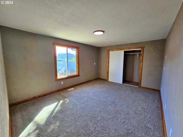 unfurnished bedroom with a closet, carpet, and a textured ceiling