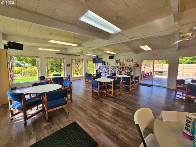 rec room featuring lofted ceiling with beams, ceiling fan, a healthy amount of sunlight, and dark hardwood / wood-style floors