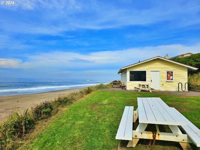 exterior space featuring a view of the beach, a water view, and a yard