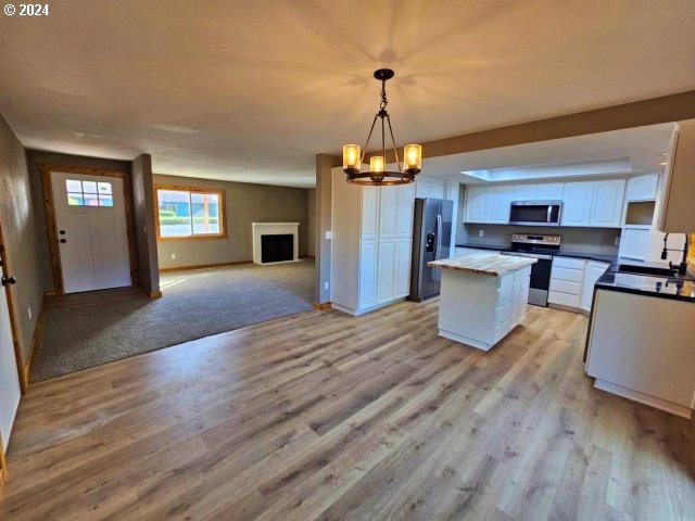 kitchen featuring sink, appliances with stainless steel finishes, a kitchen island, white cabinets, and pendant lighting