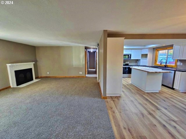 unfurnished living room featuring a textured ceiling and light hardwood / wood-style floors