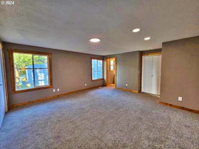 carpeted empty room with a textured ceiling