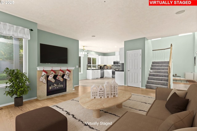 living room featuring a premium fireplace, ceiling fan, and light hardwood / wood-style floors