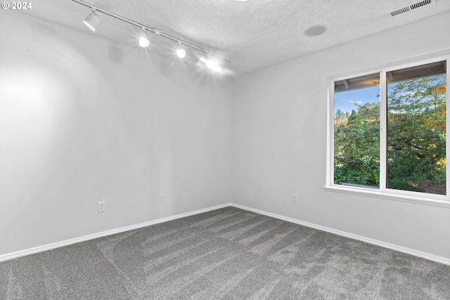 carpeted spare room with a textured ceiling and rail lighting