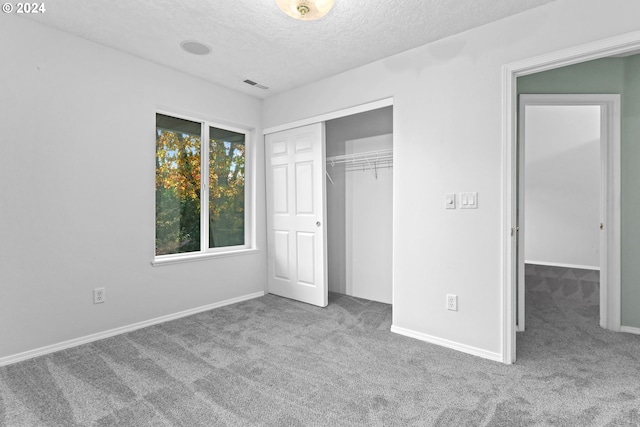 unfurnished bedroom with carpet, a textured ceiling, and a closet