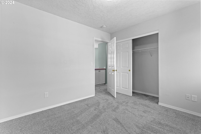 unfurnished bedroom featuring a textured ceiling, light carpet, and a closet