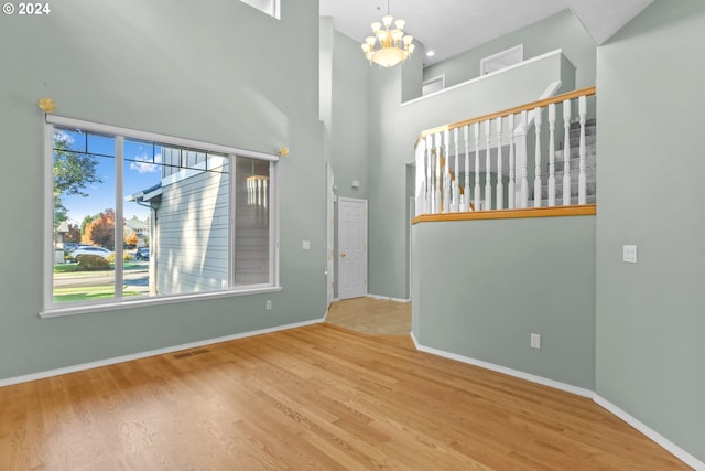 interior space with hardwood / wood-style floors, a towering ceiling, and an inviting chandelier