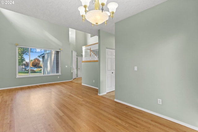 unfurnished living room featuring a notable chandelier and light hardwood / wood-style flooring