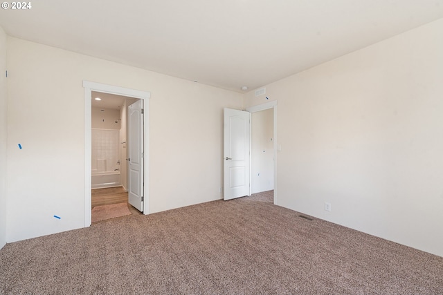 unfurnished bedroom featuring ensuite bathroom and carpet