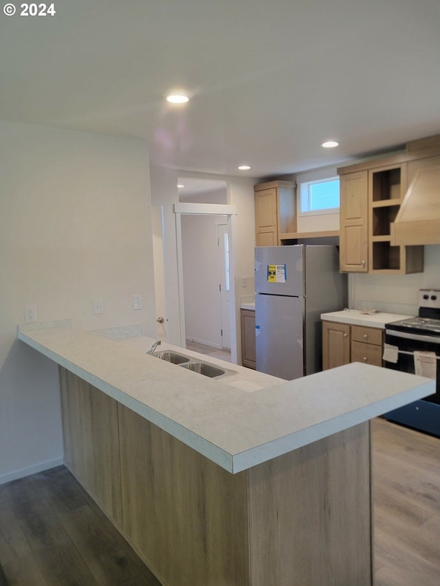 kitchen featuring electric range, sink, stainless steel fridge, extractor fan, and hardwood / wood-style flooring