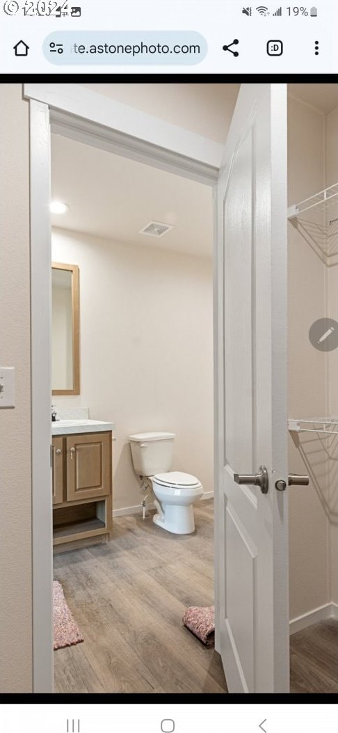 bathroom with hardwood / wood-style floors, vanity, and toilet