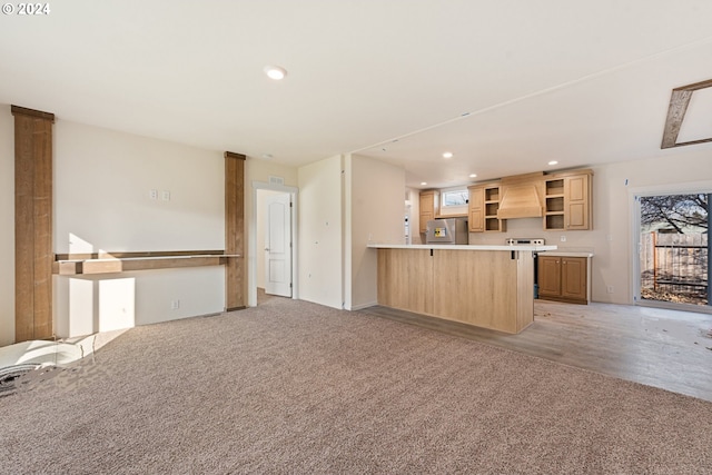 kitchen featuring light brown cabinets, kitchen peninsula, stainless steel fridge, custom range hood, and light wood-type flooring