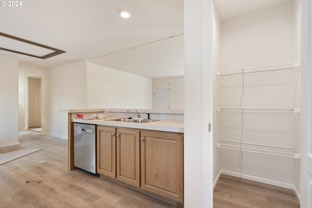 kitchen featuring stainless steel dishwasher, sink, and light hardwood / wood-style flooring