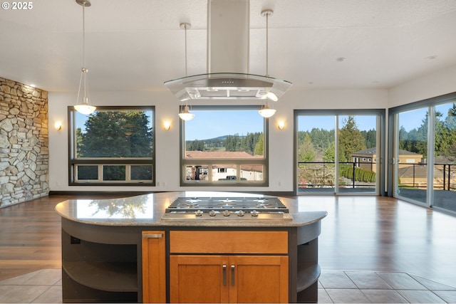 kitchen featuring hanging light fixtures, island range hood, stainless steel gas stovetop, and light stone countertops