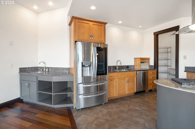 kitchen featuring sink, ventilation hood, stainless steel appliances, and dark stone countertops