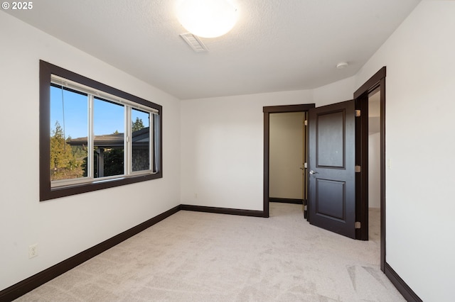 unfurnished room with light carpet and a textured ceiling