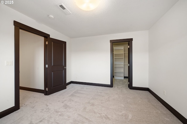 spare room featuring a textured ceiling and light carpet