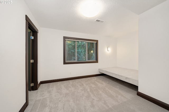 unfurnished bedroom featuring light carpet and a textured ceiling