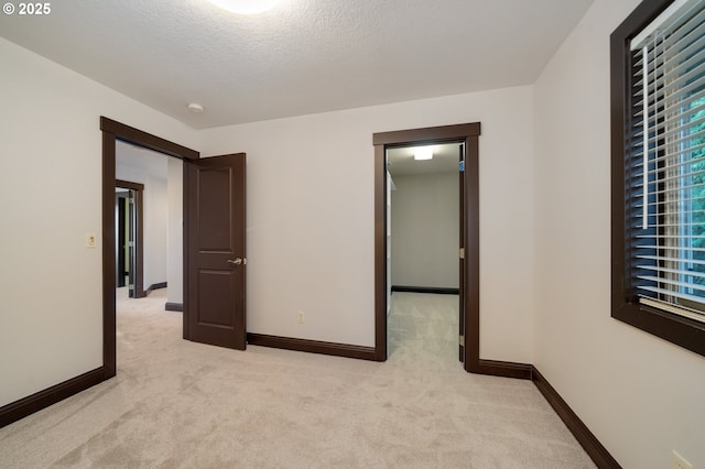 unfurnished bedroom featuring a textured ceiling and light carpet