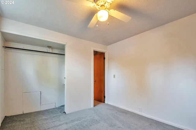 unfurnished bedroom with light carpet, a textured ceiling, a closet, and ceiling fan