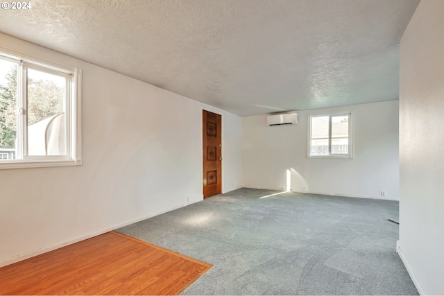 unfurnished room featuring a healthy amount of sunlight, a wall unit AC, and a textured ceiling