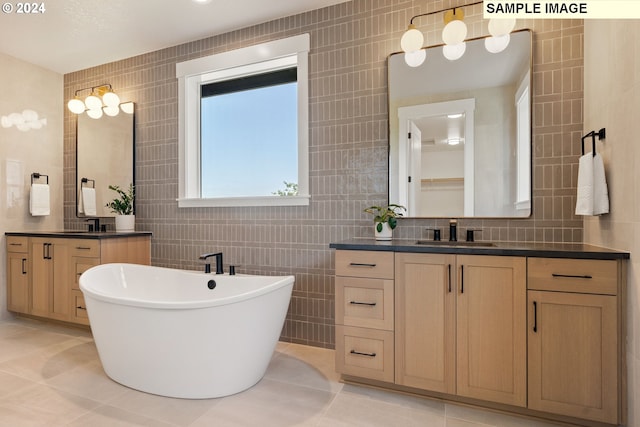 bathroom with tile patterned flooring, vanity, tile walls, and a tub