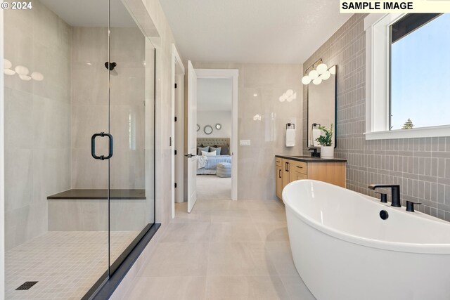 bathroom featuring tile patterned flooring, vanity, independent shower and bath, and tile walls