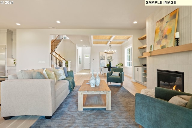 living room with hardwood / wood-style flooring, an inviting chandelier, and a tiled fireplace