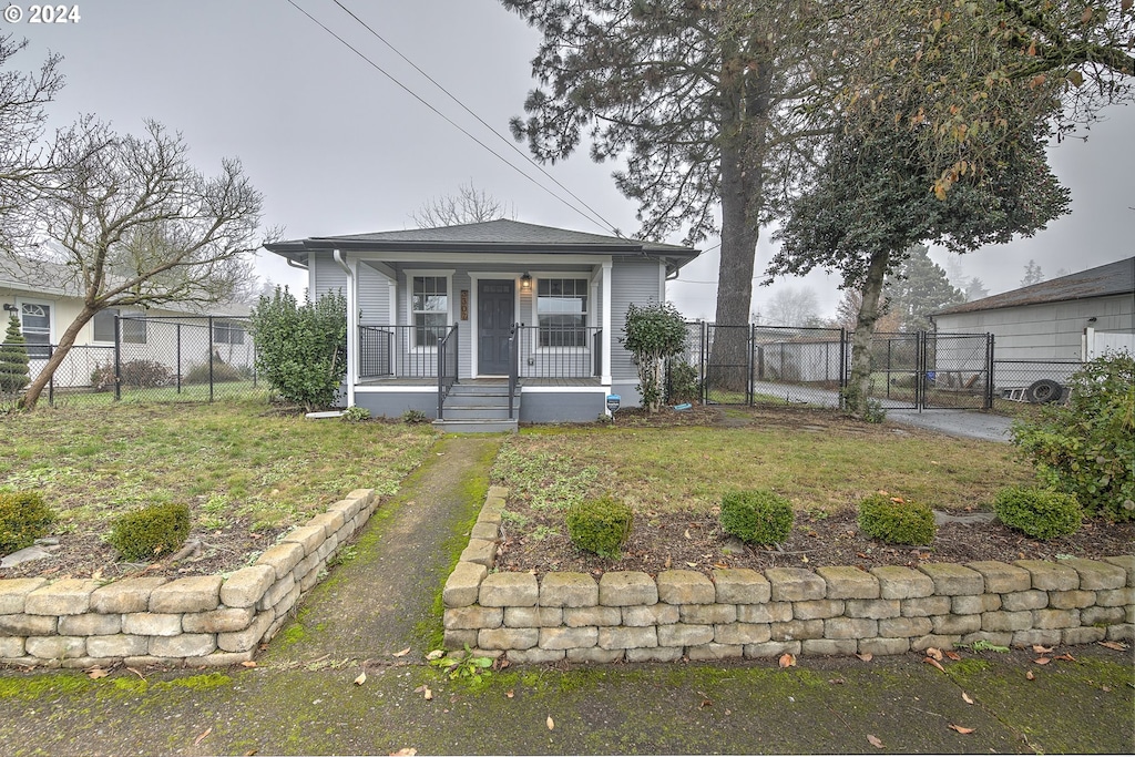 bungalow featuring covered porch and a front yard