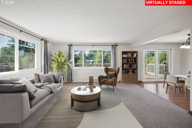 living room with light hardwood / wood-style floors, an inviting chandelier, and a textured ceiling