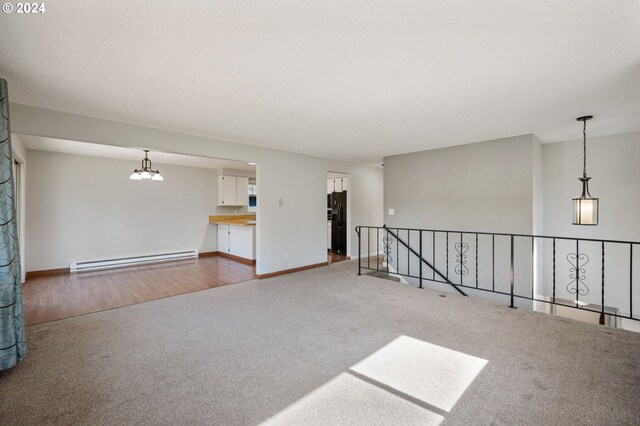 spare room featuring a baseboard radiator, an inviting chandelier, and hardwood / wood-style floors