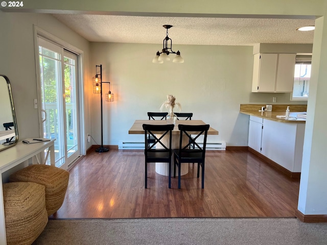 dining space featuring baseboard heating, a textured ceiling, a chandelier, and dark wood-type flooring