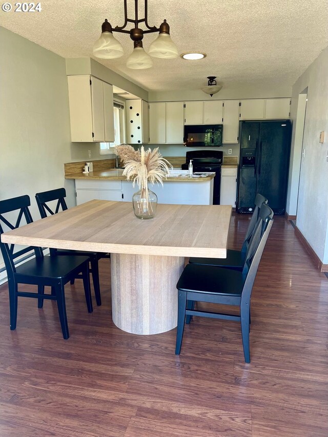 dining space featuring sink, a textured ceiling, and dark hardwood / wood-style floors