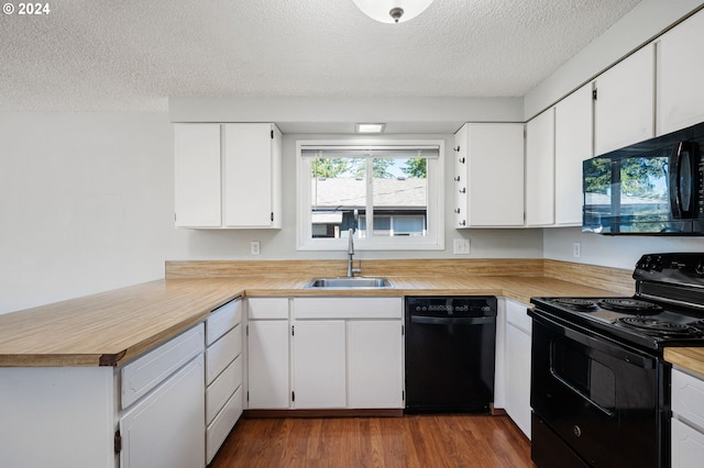 kitchen with white cabinetry, a textured ceiling, black appliances, hardwood / wood-style flooring, and sink