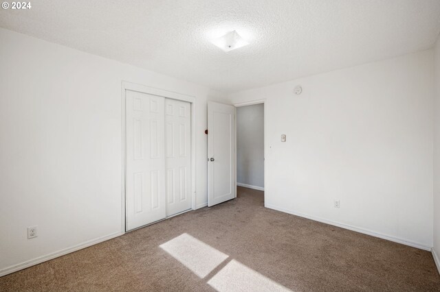 unfurnished bedroom with a closet, carpet flooring, and a textured ceiling