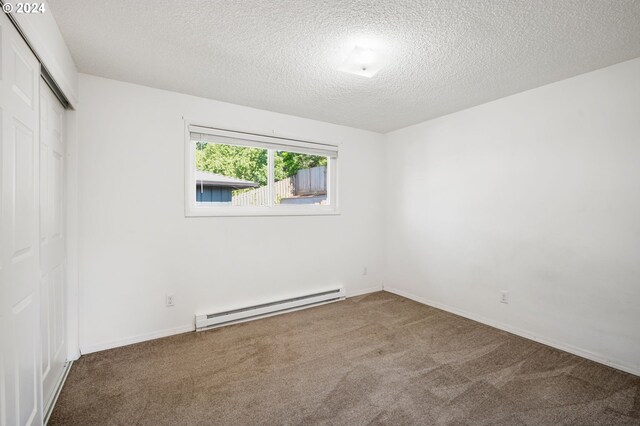 empty room featuring carpet, a baseboard radiator, and a textured ceiling