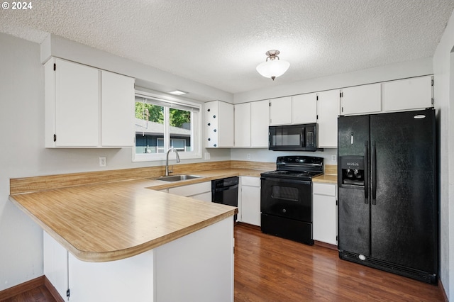 kitchen with black appliances, sink, kitchen peninsula, white cabinetry, and dark wood-type flooring